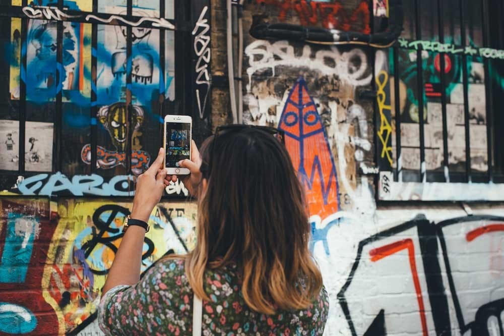 Viajar a Australia chica morena haciendo una fotografía a una pared llena de graffities